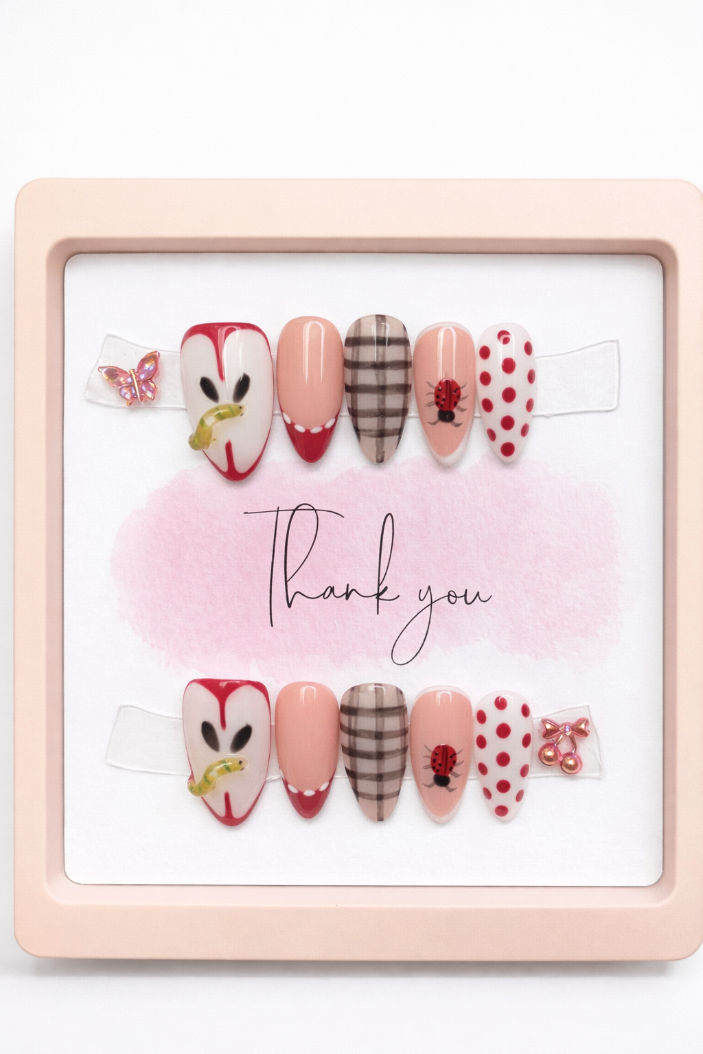 Set of decorative nail art with various designs on a pink frame.